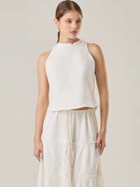 Esta blusa sin mangas refleja una elegancia natural con su cuello redondeado y acabado suave. El diseño se enfoca en la simplicidad, resaltando su frescura y ligereza. Perfecta para combinar con faldas o pantalones, ofrece una versatilidad ideal para días cálidos o eventos casuales.