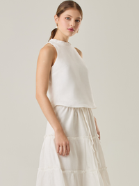 Esta blusa sin mangas refleja una elegancia natural con su cuello redondeado y acabado suave. El diseño se enfoca en la simplicidad, resaltando su frescura y ligereza. Perfecta para combinar con faldas o pantalones, ofrece una versatilidad ideal para días cálidos o eventos casuales.