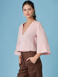Blusa rosa de estilo minimalista con escote en V y boton decorativo. La blusa micaela rosa es una prenda versatil que eleva cualquier look gracias a su diseño delicado y moderno.