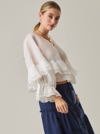 Blusa fluida con un diseño envolvente y detalles en capas que aportan volumen y movimiento. Su escote en V con botones añade un toque delicado, mientras que las mangas amplias con terminación elástica complementan su estilo sofisticado y femenino.

Color: Blanco perla

Material: 57% Rayón 43% Poliester.

Cuidado: Lavar a mano con jabón suave, por separado. No dejar en remojo. Planchar a temperatura alta.