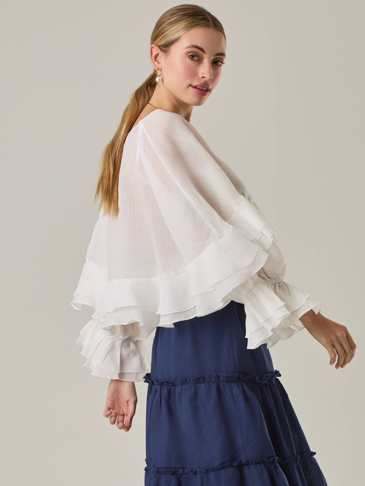 Blusa fluida con un diseño envolvente y detalles en capas que aportan volumen y movimiento. Su escote en V con botones añade un toque delicado, mientras que las mangas amplias con terminación elástica complementan su estilo sofisticado y femenino.

Color: Blanco perla

Material: 57% Rayón 43% Poliester.