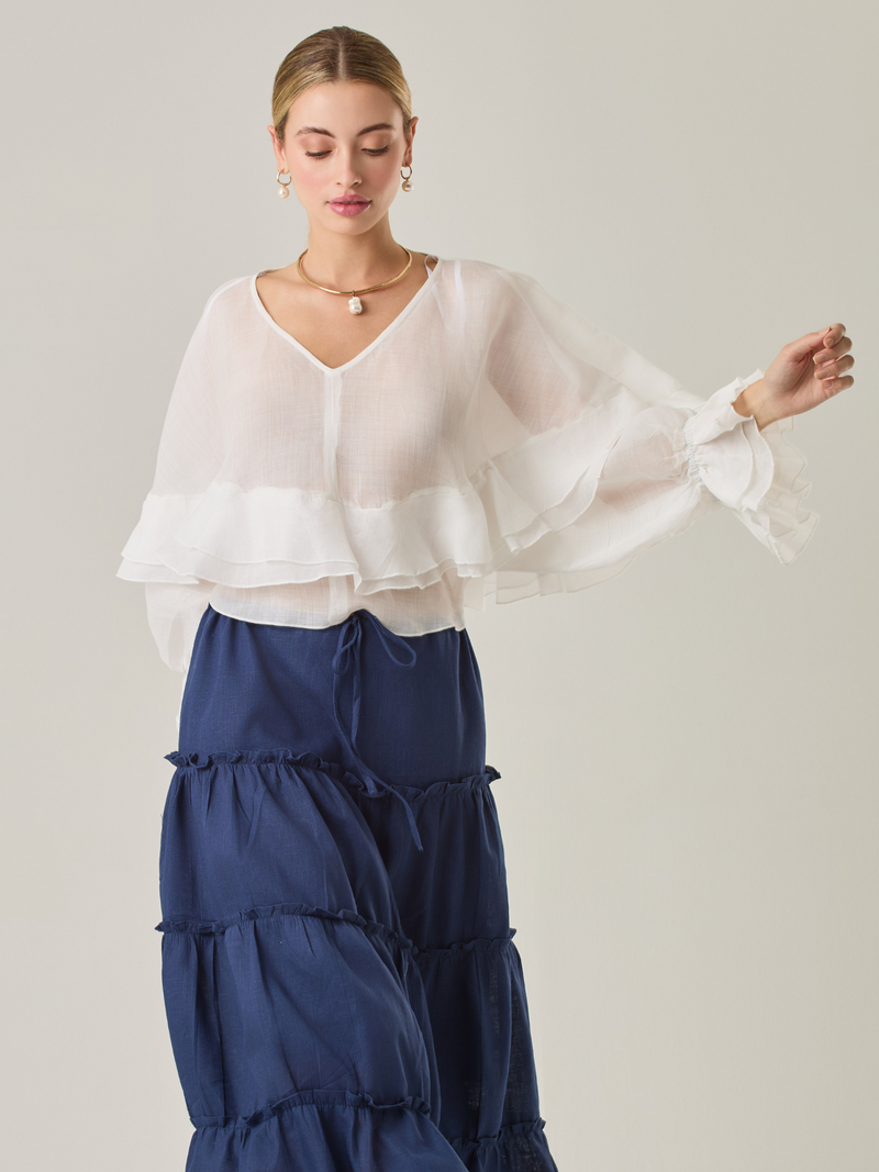 Blusa fluida con un diseño envolvente y detalles en capas que aportan volumen y movimiento. Su escote en V con botones añade un toque delicado, mientras que las mangas amplias con terminación elástica complementan su estilo sofisticado y femenino.

Color: Blanco perla

Material: 57% Rayón 43% Poliester.