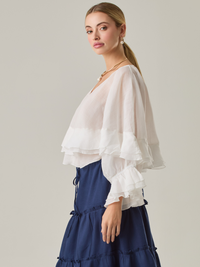 Blusa fluida con un diseño envolvente y detalles en capas que aportan volumen y movimiento. Su escote en V con botones añade un toque delicado, mientras que las mangas amplias con terminación elástica complementan su estilo sofisticado y femenino.

Color: Blanco perla

Material: 57% Rayón 43% Poliester.

Cuidado: Lavar a mano con jabón suave, por separado. No dejar en remojo. Planchar a temperatura alta.