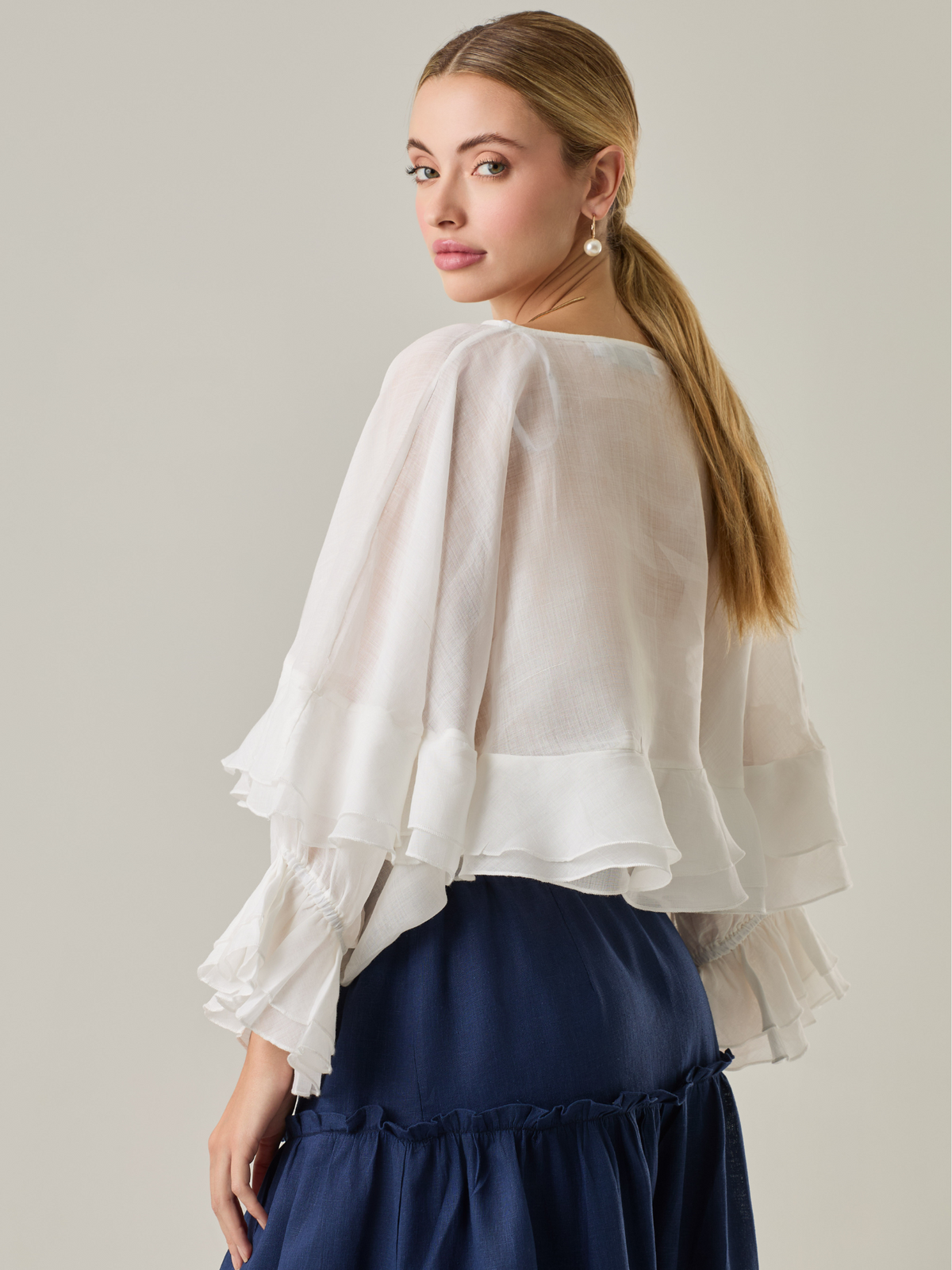 Blusa fluida con un diseño envolvente y detalles en capas que aportan volumen y movimiento. Su escote en V con botones añade un toque delicado, mientras que las mangas amplias con terminación elástica complementan su estilo sofisticado y femenino.

Color: Blanco perla

Material: 57% Rayón 43% Poliester.