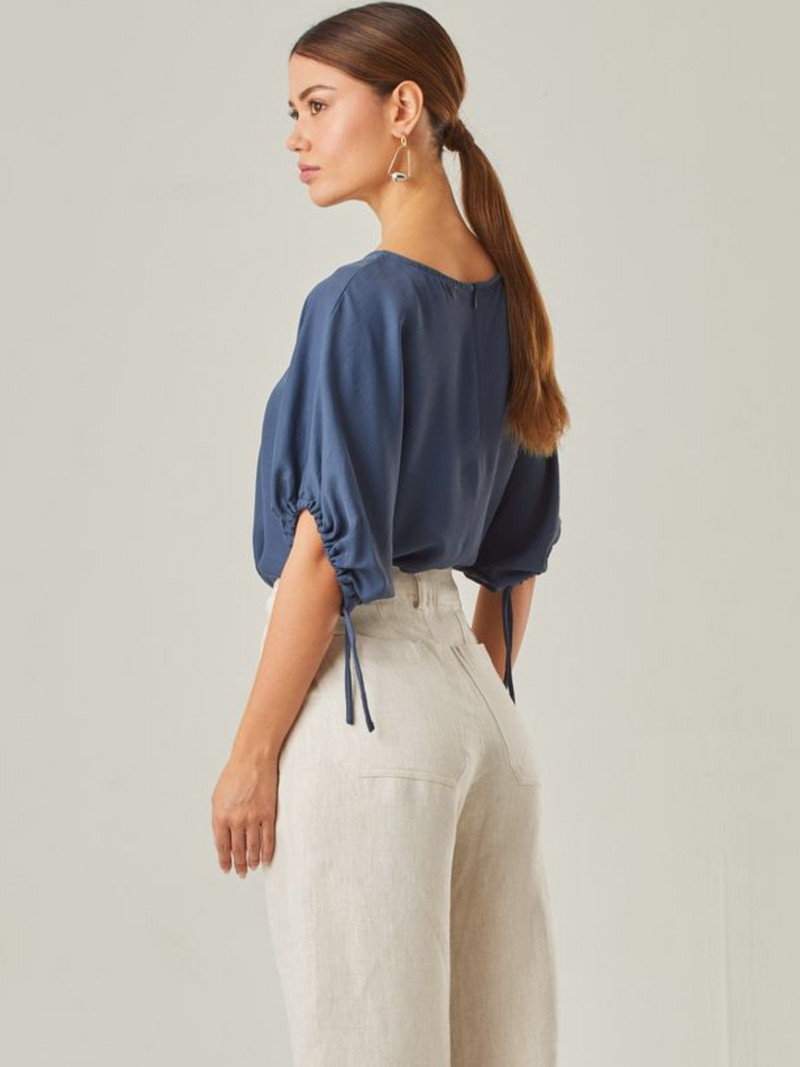 Blusa con un estilo relajado que combina comodidad y elegancia. Las mangas voluminosas, ajustables con delicados lazos, le otorgan un toque versátil, mientras que su corte fluido favorece una caída natural. Perfecta para crear looks modernos y atemporales.
