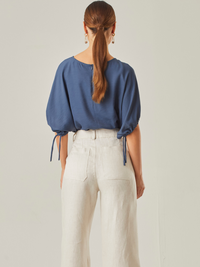 Blusa con un estilo relajado que combina comodidad y elegancia. Las mangas voluminosas, ajustables con delicados lazos, le otorgan un toque versátil, mientras que su corte fluido favorece una caída natural. Perfecta para crear looks modernos y atemporales.