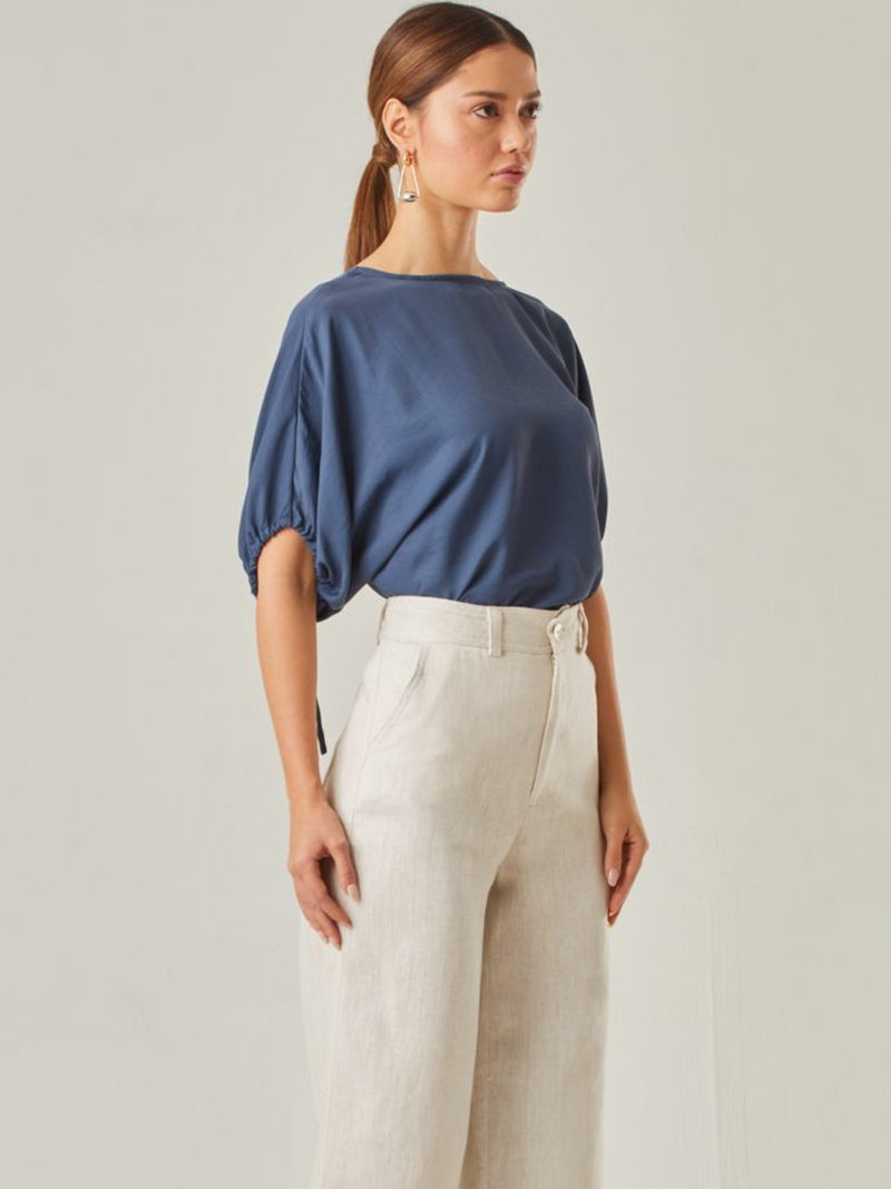 Blusa con un estilo relajado que combina comodidad y elegancia. Las mangas voluminosas, ajustables con delicados lazos, le otorgan un toque versátil, mientras que su corte fluido favorece una caída natural. Perfecta para crear looks modernos y atemporales.