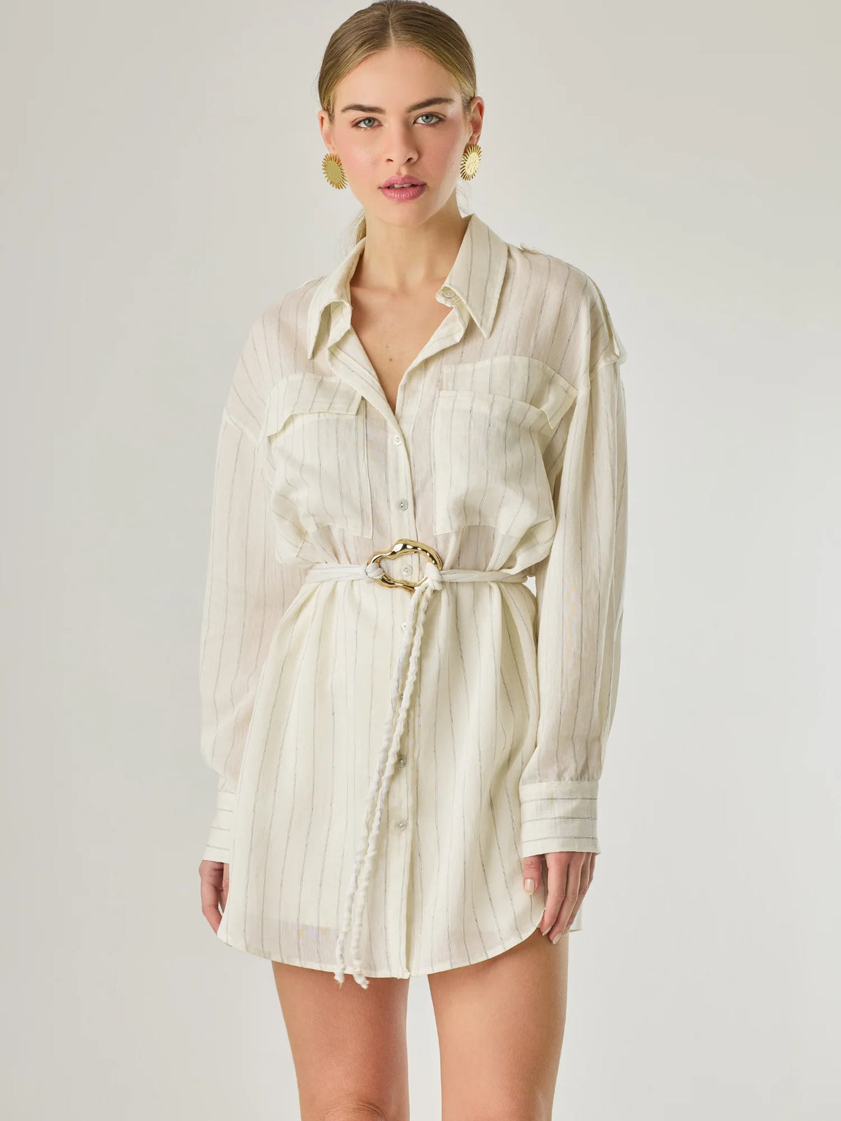 Blusa tipo camisera de manga larga con sutiles rayas y cinturón trenzado que define la figura. Su diseño ligero y relajado ofrece un estilo casual con toques elegantes, ideal para llevar con faldas o pantalones en looks versátiles y modernos.

Detalles:

Color: Blanco

Material: 77% Rayon 23% Nylon

Características: Incluye cinturón a tono.