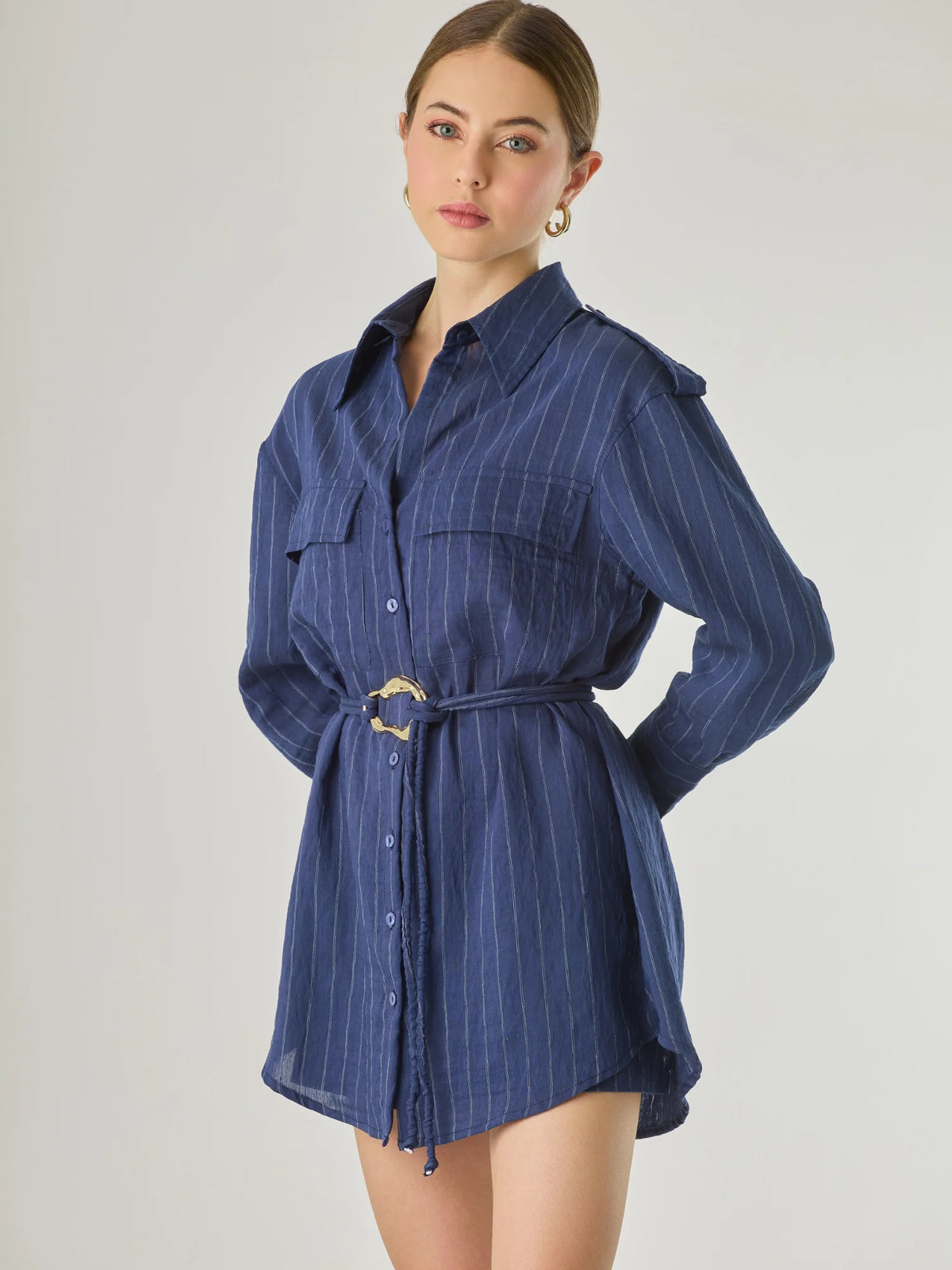 Blusa tipo camisera de manga larga con sutiles rayas y cinturón trenzado que define la figura. Su diseño ligero y relajado ofrece un estilo casual con toques elegantes, ideal para llevar con faldas o pantalones en looks versátiles y modernos.

Detalles:

Color: Navy

Material: 77% Rayon 23% Nylon

Características: Incluye cinturón a tono.