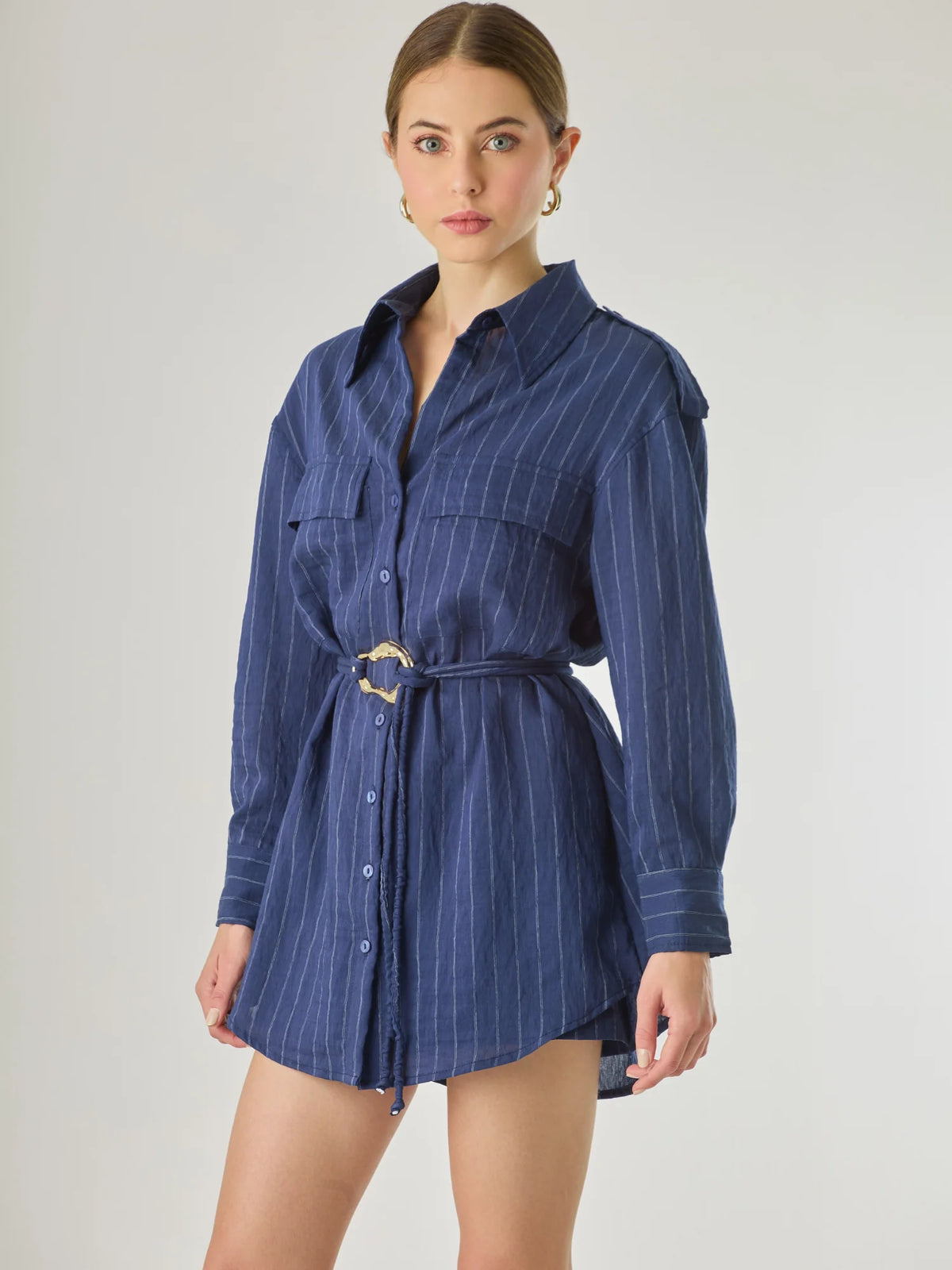 Blusa tipo camisera de manga larga con sutiles rayas y cinturón trenzado que define la figura. Su diseño ligero y relajado ofrece un estilo casual con toques elegantes, ideal para llevar con faldas o pantalones en looks versátiles y modernos.

Detalles:

Color: Navy

Material: 77% Rayon 23% Nylon

Características: Incluye cinturón a tono.