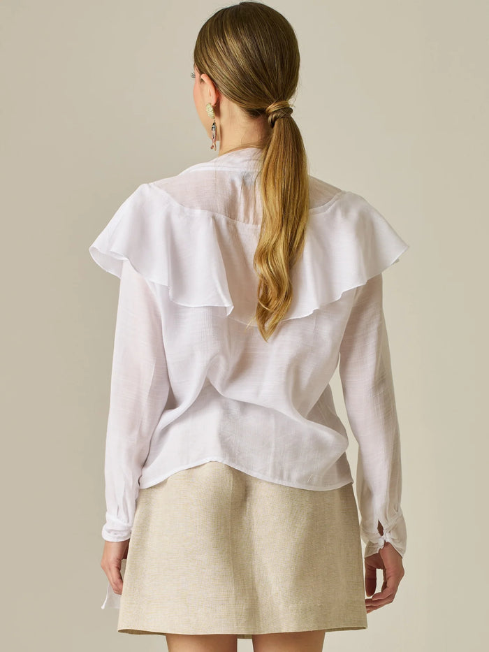 Blusa de manga larga con detalle de volantes en el escote y lazo largo para anudar. Su diseño ligero y delicado aporta movimiento y sofisticación, ideal para un look femenino con un aire romántico y moderno.

Detalles: