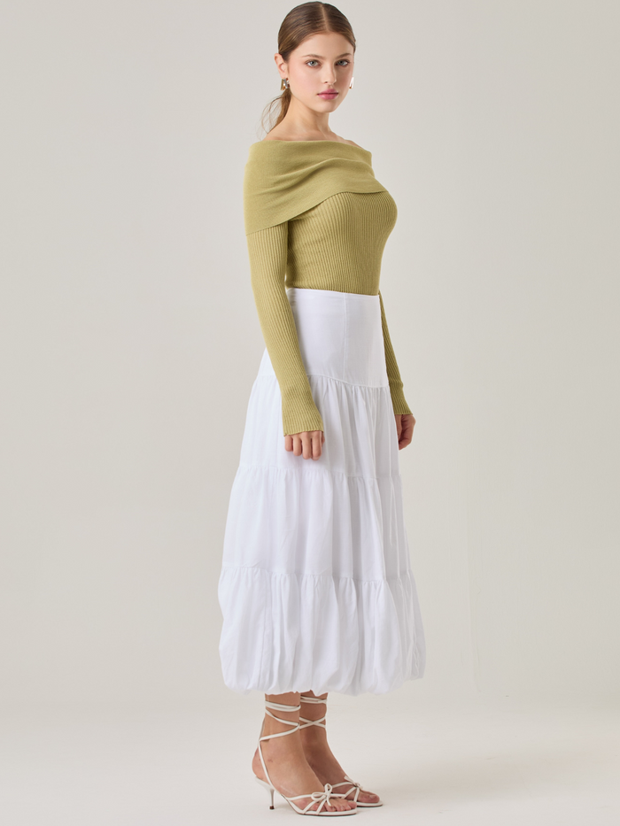 Esta es una falda blanca de largo midi con un diseño en capas que crea un efecto abombado en la parte inferior. Está hecha en una tela liviana y con caída. Tiene un estilo romántico y femenino, ideal para combinar con blusas ajustadas o crop tops. En la imagen se lleva con un suéter off-shoulder que le da un look sofisticado.

Detalles:

Color: Blanco