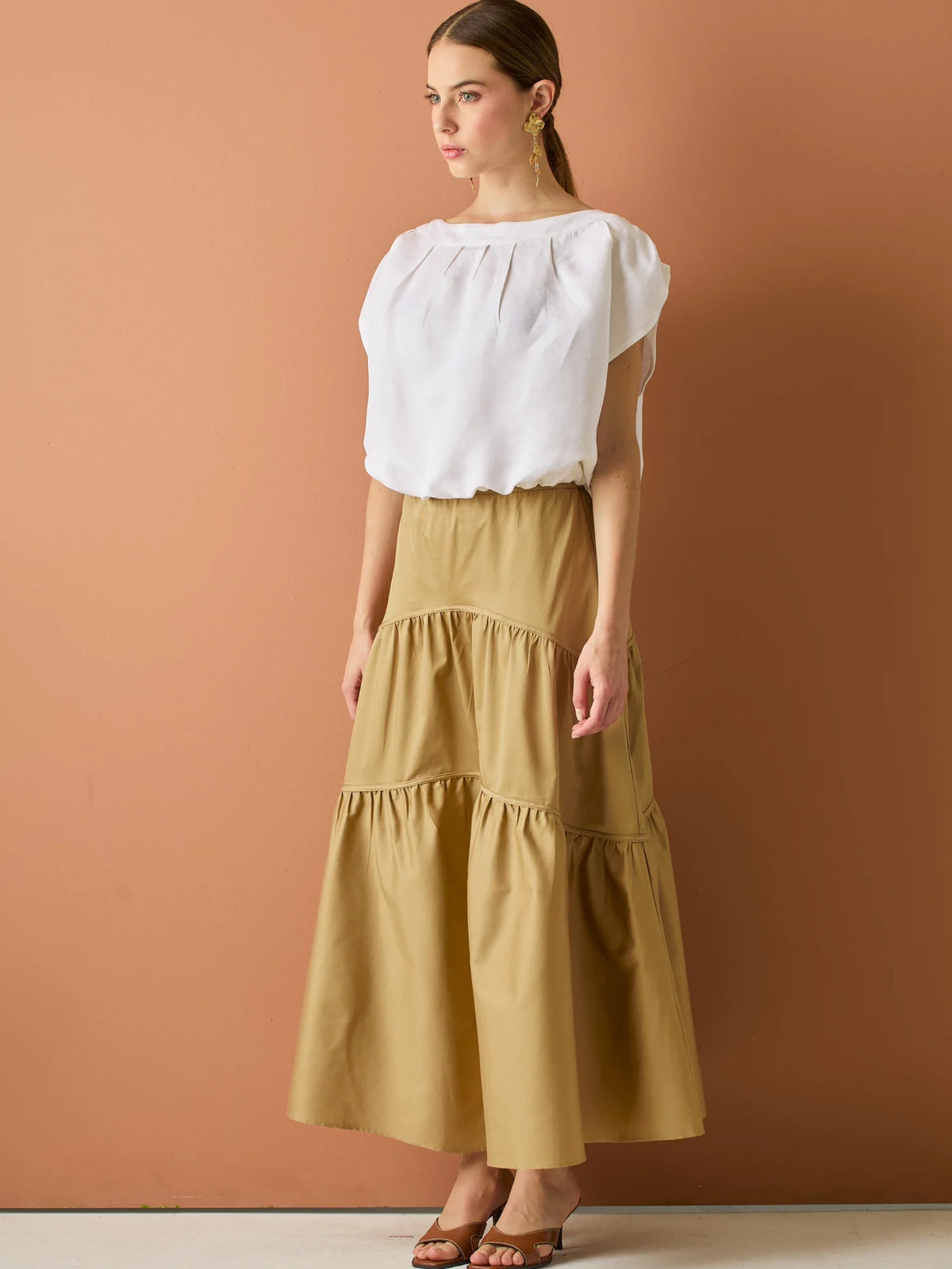 Falda larga con diseño&nbsp; de volantes suaves que aportan movimiento y volumen. Su silueta amplia y estructura liviana la hacen perfecta para un look relajado y sofisticado, ideal para combinar con blusas ligeras y crear estilismos con encanto natural.

Detalles:

Color: Camel