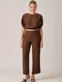 El Pantalón Largo Agostina Café presenta un diseño de tiro alto con caída recta que estiliza la figura. Ideal para looks elegantes o casuales, es una prenda versátil perfecta para el día a día.