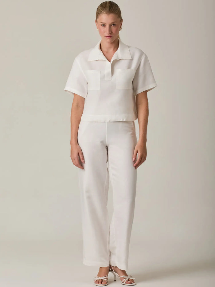 Pantalón largo para mujer en color blanco con silueta recta y tiro medio que estiliza la figura. Su diseño limpio y versátil lo convierte en una prenda ideal para looks elegantes, casuales o de oficina, fácil de combinar con blusas y tops de la colección.