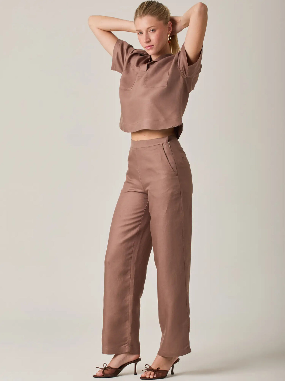 Pantalon largo en tono cafe con diseño atemporal y lineas depuradas. Una prenda esencial para un guardarropa versatil, ideal para looks monocromaticos o combinaciones neutras con un toque sofisticado.