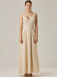 Vestido largo sin mangas con escote sutilmente curvado. El talle entallado contrasta con la amplitud de la falda, creando una silueta fluida y elegante. Una propuesta fresca, pensada para climas cálidos o eventos al aire libre, con un aire relajado que no pierde sofisticación.