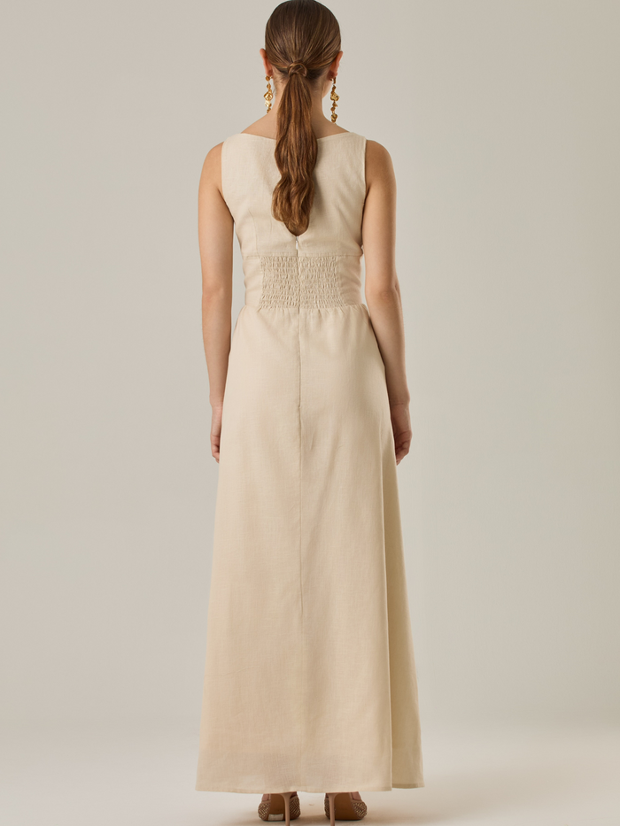 Vestido largo sin mangas con escote sutilmente curvado. El talle entallado contrasta con la amplitud de la falda, creando una silueta fluida y elegante. Una propuesta fresca, pensada para climas cálidos o eventos al aire libre, con un aire relajado que no pierde sofisticación.