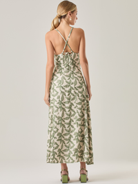 Este vestido largo es una opción fresca y sofisticada. Tiene un escote en V que realza la silueta y tirantes cruzados en la espalda que le dan un toque especial. Su estampado de hojas en tonos verdes resalta sobre la base clara, creando un contraste armonioso. La falda amplia y la cintura ajustable ofrecen comodidad y movimiento, ideal para climas cálidos y ocasiones especiales.
