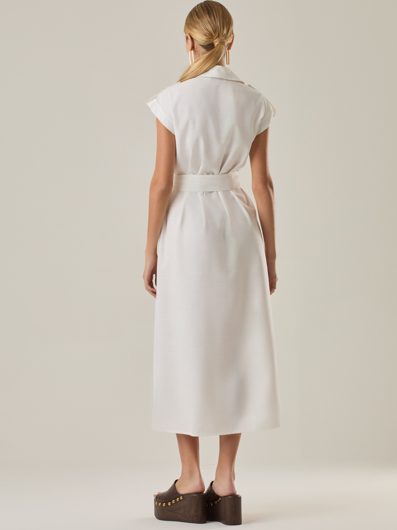 Vestido con mangas con botonadura frontal y cinturón a tono. Tiene bolsillos tipo parche en el pecho que acentúan su aire utilitario, mientras que el largo  y los botones metálicos le dan un acabado elegante y atemporal. Perfecto para un look sofisticado de día.