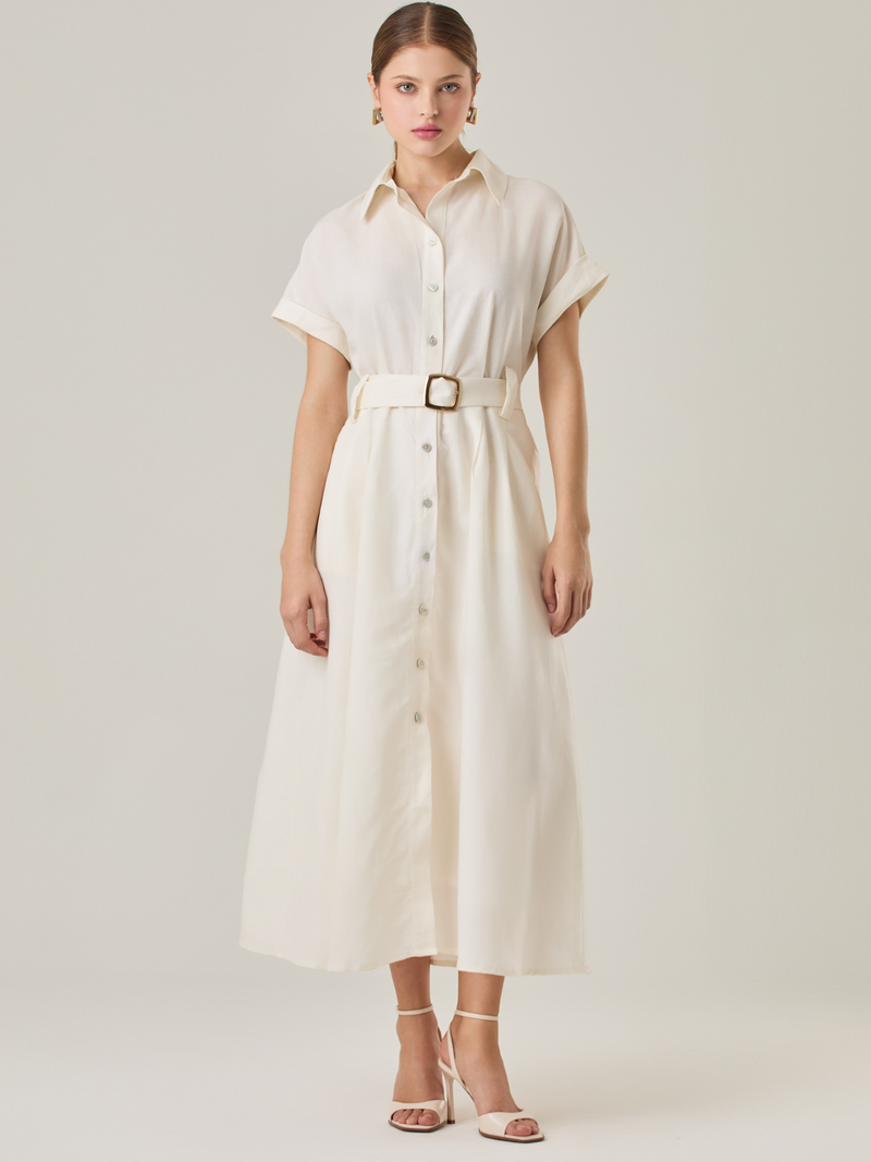 Vestido camisero de silueta midi con botonadura frontal completa y mangas cortas dobladas que aportan un aire relajado. Incorpora un cinturón del mismo material con hebilla forrada que define la cintura y realza la figura. Su estructura lo hace una prenda práctica y atemporal, perfecta para ocasiones casuales o más sofisticadas según cómo se combine.

Detalles:

Color: Blanco Perla

Material: 77% Tencel 23% Lino