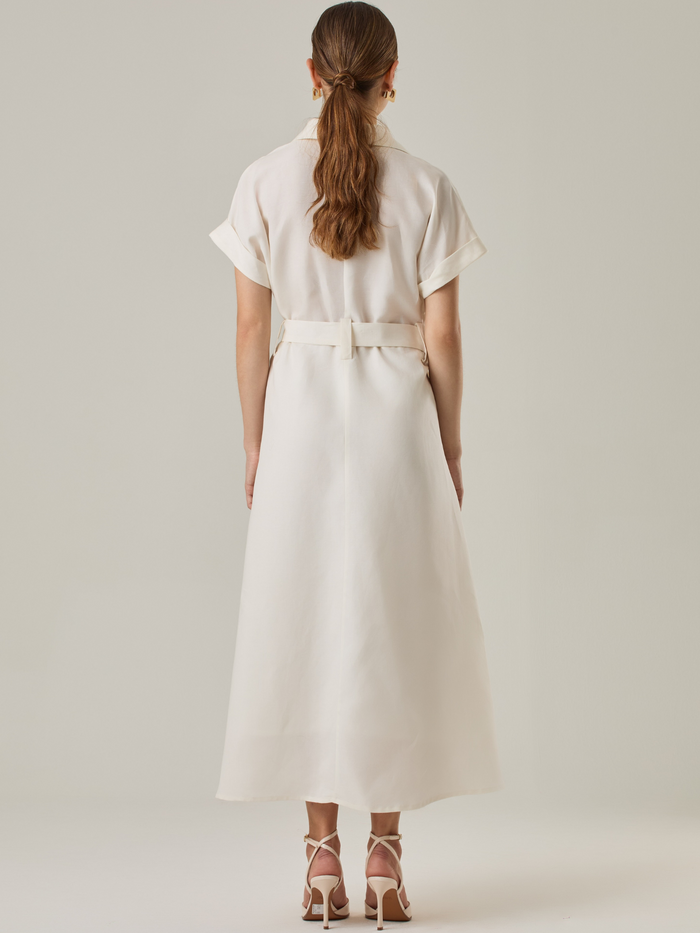 Vestido camisero de silueta midi con botonadura frontal completa y mangas cortas dobladas que aportan un aire relajado. Incorpora un cinturón del mismo material con hebilla forrada que define la cintura y realza la figura. Su estructura lo hace una prenda práctica y atemporal, perfecta para ocasiones casuales o más sofisticadas según cómo se combine.