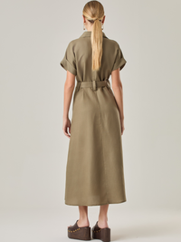 Vestido camisero de silueta midi con botonadura frontal completa y mangas cortas dobladas que aportan un aire relajado. Incorpora un cinturón del mismo material con hebilla forrada que define la cintura y realza la figura. Su estructura lo hace una prenda práctica y atemporal, perfecta para ocasiones casuales o más sofisticadas según cómo se combine.