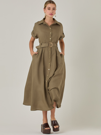 Vestido camisero de silueta midi con botonadura frontal completa y mangas cortas dobladas que aportan un aire relajado. Incorpora un cinturón del mismo material con hebilla forrada que define la cintura y realza la figura. Su estructura lo hace una prenda práctica y atemporal, perfecta para ocasiones casuales o más sofisticadas según cómo se combine.