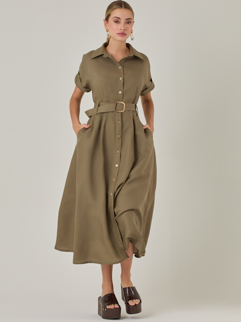 Vestido camisero de silueta midi con botonadura frontal completa y mangas cortas dobladas que aportan un aire relajado. Incorpora un cinturón del mismo material con hebilla forrada que define la cintura y realza la figura. Su estructura lo hace una prenda práctica y atemporal, perfecta para ocasiones casuales o más sofisticadas según cómo se combine.