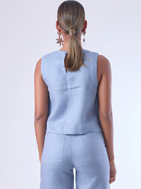 Blusa sin mangas de corte recto y silueta relajada. Tiene cuello redondo cerrado y un diseño limpio sin detalles visibles, lo que le da un estilo minimalista y moderno. El largo llega justo a la cintura, ideal para llevar por fuera o combinada con prendas de talle alto para un look fresco y sofisticado