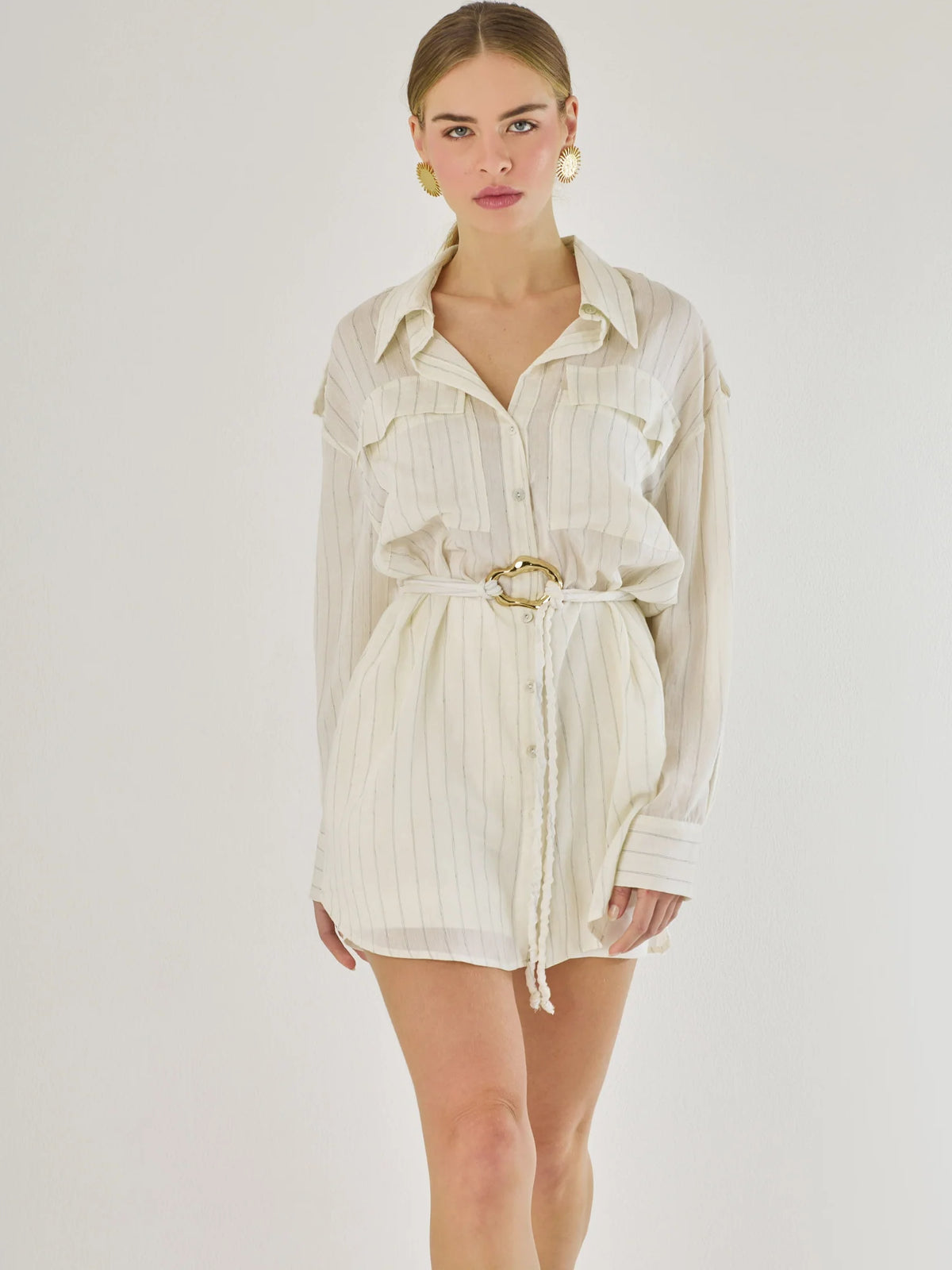 Blusa tipo camisera de manga larga con sutiles rayas y cinturón trenzado que define la figura. Su diseño ligero y relajado ofrece un estilo casual con toques elegantes, ideal para llevar con faldas o pantalones en looks versátiles y modernos.

Detalles:

Color: Blanco

Material: 77% Rayon 23% Nylon

Características: Incluye cinturón a tono.