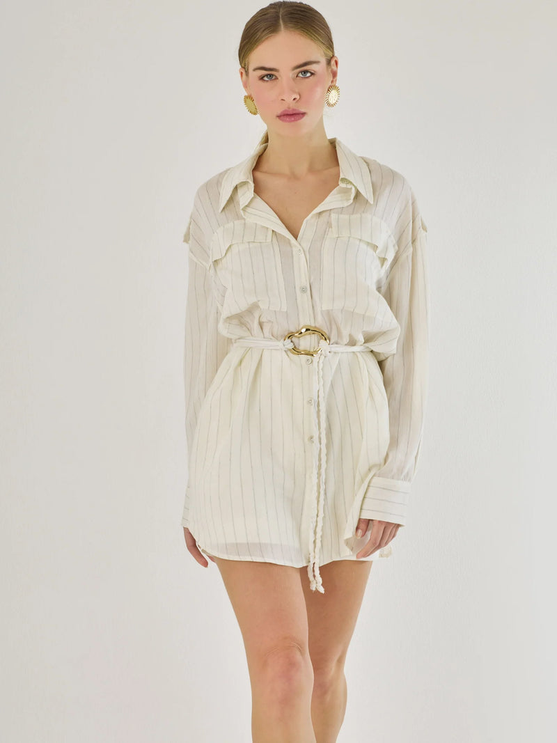 Blusa tipo camisera de manga larga con sutiles rayas y cinturón trenzado que define la figura. Su diseño ligero y relajado ofrece un estilo casual con toques elegantes, ideal para llevar con faldas o pantalones en looks versátiles y modernos.

Detalles:

Color: Blanco

Material: 77% Rayon 23% Nylon

Características: Incluye cinturón a tono.