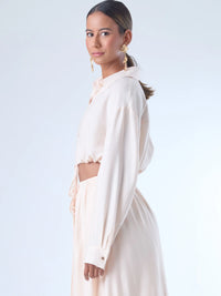 Blusa de corte relajado y largo cropped, con manga larga y puños con botones. Tiene cuello clásico camisero y una botonadura frontal. La prenda se ajusta a la cintura mediante un ligero fruncido con cordón interno, creando un efecto ablusado. Su estilo es casual con un toque sofisticado y femenino.

Detalles:

Color: Curuba

Material:18% Nylon 82% Rayón
