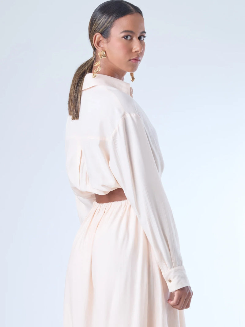 Blusa de corte relajado y largo cropped, con manga larga y puños con botones. Tiene cuello clásico camisero y una botonadura frontal. La prenda se ajusta a la cintura mediante un ligero fruncido con cordón interno, creando un efecto ablusado. Su estilo es casual con un toque sofisticado y femenino.

Detalles:

Color: Curuba

Material:18% Nylon 82% Rayón