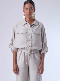 Relajada pero estructurada, esta blusa de silueta amplia combina un diseño utilitario con detalles refinados. Presenta bolsillos de solapa en el pecho, mangas con opción de ajuste y una botonadura dorada que aporta un toque de brillo sutil. Ideal para estilismos casuales con elegancia natural, o para elevar conjuntos relajados con una prenda clave y atemporal.