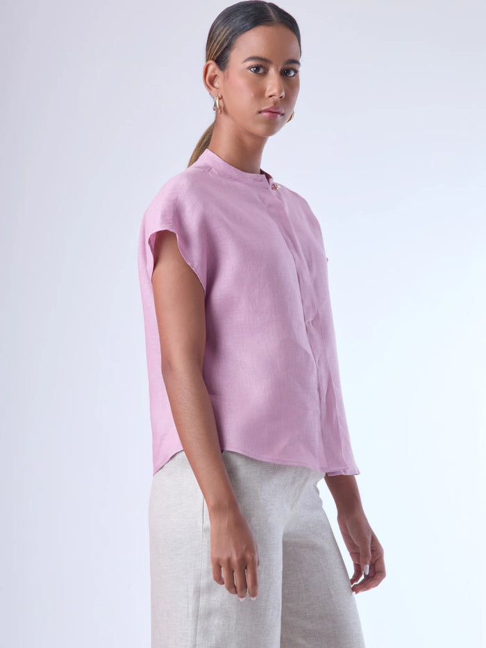 Blusa de silueta recta con manga corta tipo caída y estructura relajada. Cuenta con cuello que se cierra con un pequeño broche metálico decorativos estilo sobrio la hace versátil y elegante, ideal para atuendos casuales o más refinados.
