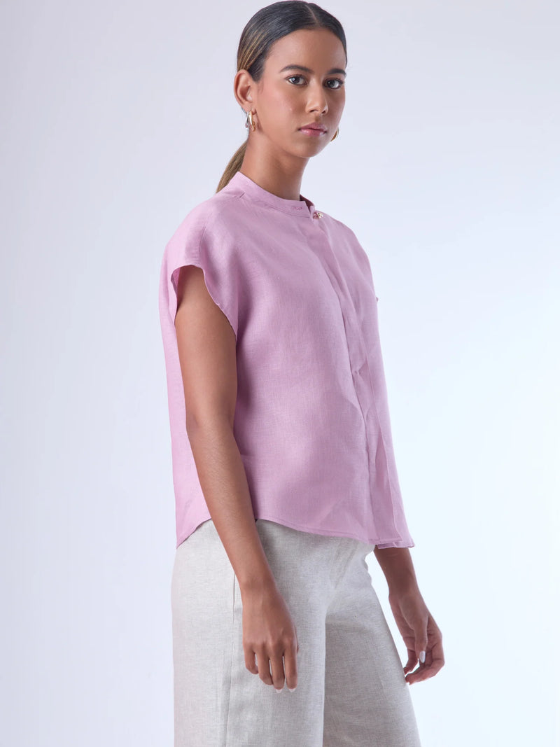 Blusa de silueta recta con manga corta tipo caída y estructura relajada. Cuenta con cuello que se cierra con un pequeño broche metálico decorativos estilo sobrio la hace versátil y elegante, ideal para atuendos casuales o más refinados.