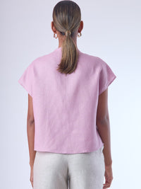 Blusa de silueta recta con manga corta tipo caída y estructura relajada. Cuenta con cuello que se cierra con un pequeño broche metálico decorativos estilo sobrio la hace versátil y elegante, ideal para atuendos casuales o más refinados.
