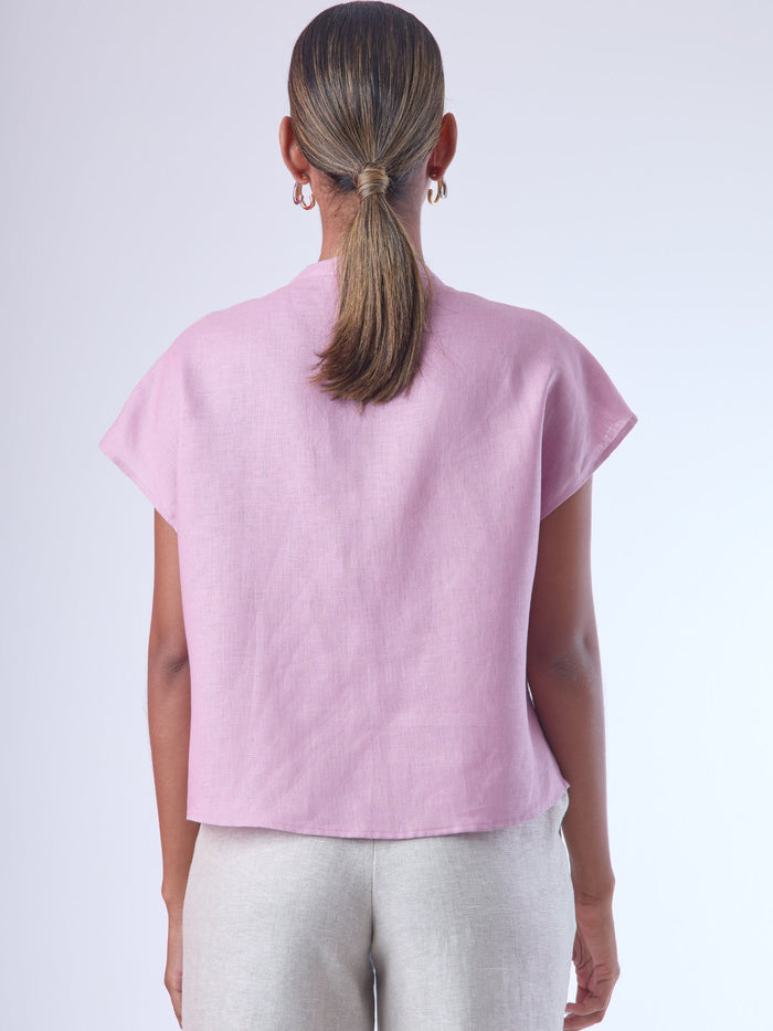 Blusa de silueta recta con manga corta tipo caída y estructura relajada. Cuenta con cuello que se cierra con un pequeño broche metálico decorativos estilo sobrio la hace versátil y elegante, ideal para atuendos casuales o más refinados.