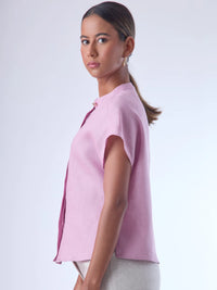 Blusa de silueta recta con manga corta tipo caída y estructura relajada. Cuenta con cuello que se cierra con un pequeño broche metálico decorativos estilo sobrio la hace versátil y elegante, ideal para atuendos casuales o más refinados.