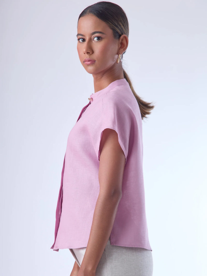 Blusa de silueta recta con manga corta tipo caída y estructura relajada. Cuenta con cuello que se cierra con un pequeño broche metálico decorativos estilo sobrio la hace versátil y elegante, ideal para atuendos casuales o más refinados.