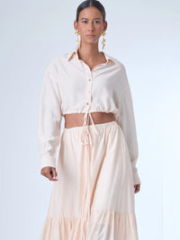 Blusa de corte relajado y largo cropped, con manga larga y puños con botones. Tiene cuello clásico camisero y una botonadura frontal. La prenda se ajusta a la cintura mediante un ligero fruncido con cordón interno, creando un efecto ablusado. Su estilo es casual con un toque sofisticado y femenino.

Detalles:

Color: Curuba

Material:18% Nylon 82% Rayón