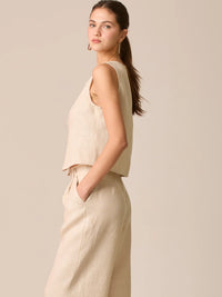 Blusa tipo chaleco sin mangas, con escote redondo y cierre frontal de botones forrados, entallada en la parte superior y con dobladillo ligeramente curvado que aporta un acabado elegante y estructurado