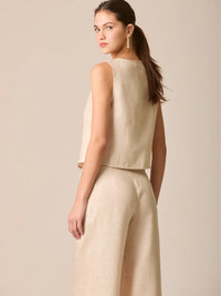 Blusa tipo chaleco sin mangas, con escote redondo y cierre frontal de botones forrados, entallada en la parte superior y con dobladillo ligeramente curvado que aporta un acabado elegante y estructurado
