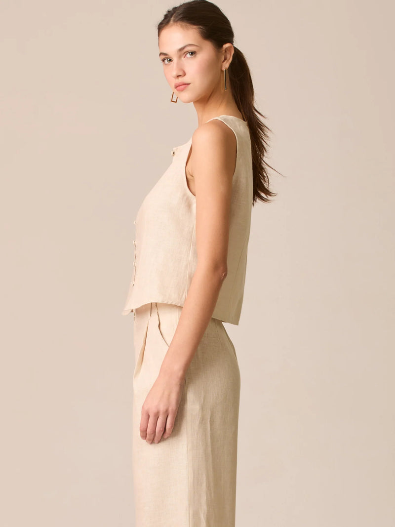 Blusa tipo chaleco sin mangas, con escote redondo y cierre frontal de botones forrados, entallada en la parte superior y con dobladillo ligeramente curvado que aporta un acabado elegante y estructurado