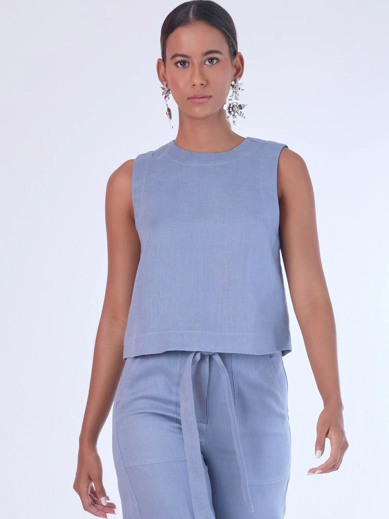 Blusa sin mangas de corte recto y silueta relajada. Tiene cuello redondo cerrado y un diseño limpio sin detalles visibles, lo que le da un estilo minimalista y moderno. El largo llega justo a la cintura, ideal para llevar por fuera o combinada con prendas de talle alto para un look fresco y sofisticado