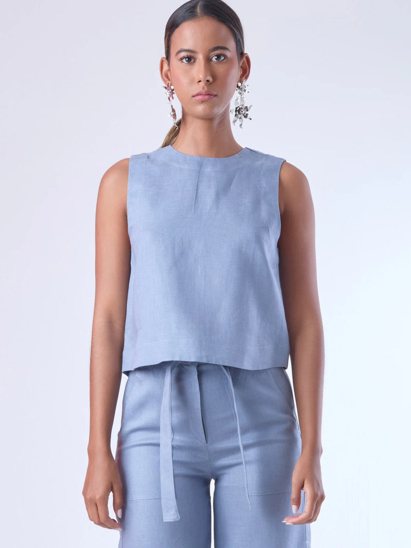 Blusa sin mangas de corte recto y silueta relajada. Tiene cuello redondo cerrado y un diseño limpio sin detalles visibles, lo que le da un estilo minimalista y moderno. El largo llega justo a la cintura, ideal para llevar por fuera o combinada con prendas de talle alto para un look fresco y sofisticado