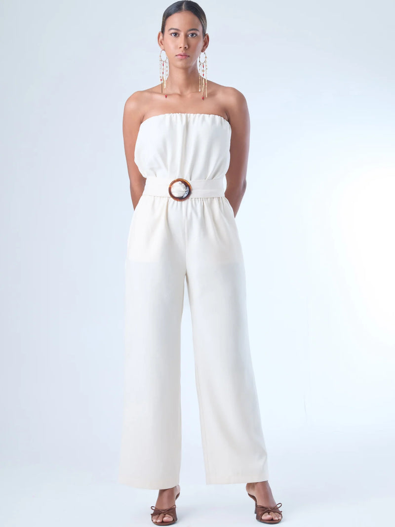 Jumpsuit sin tirantes de corte largo y silueta fluida. El diseño superior tiene un efecto fruncido en el escote elástico, que se ajusta suavemente al cuerpo. En la cintura destaca un cinturón ancho con hebilla redonda que define la figura. El pantalón cae recto hasta el tobillo con un estilo relajado y elegante. Ideal para un look moderno con aire minimalista.
