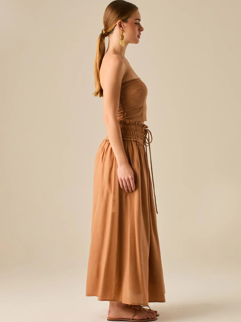 Falda larga de tiro alto con pretina fruncida y lazo ajustable, ideal para un look relajado con elegancia sutil. Su caída fluida y textura ligera aportan movimiento y frescura, perfecta para estilismos sofisticados con esencia natural.

Detalles:

Color: Camel

Material: 82% Rayon 18% Nylon