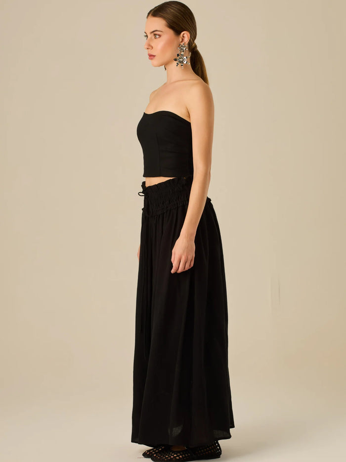 Falda larga de tiro alto con pretina fruncida y lazo ajustable, ideal para un look relajado con elegancia sutil. Su caída fluida y textura ligera aportan movimiento y frescura, perfecta para estilismos sofisticados con esencia natural.

Detalles:

Color: Negro

Material: 82% Rayon 18% Nylon
